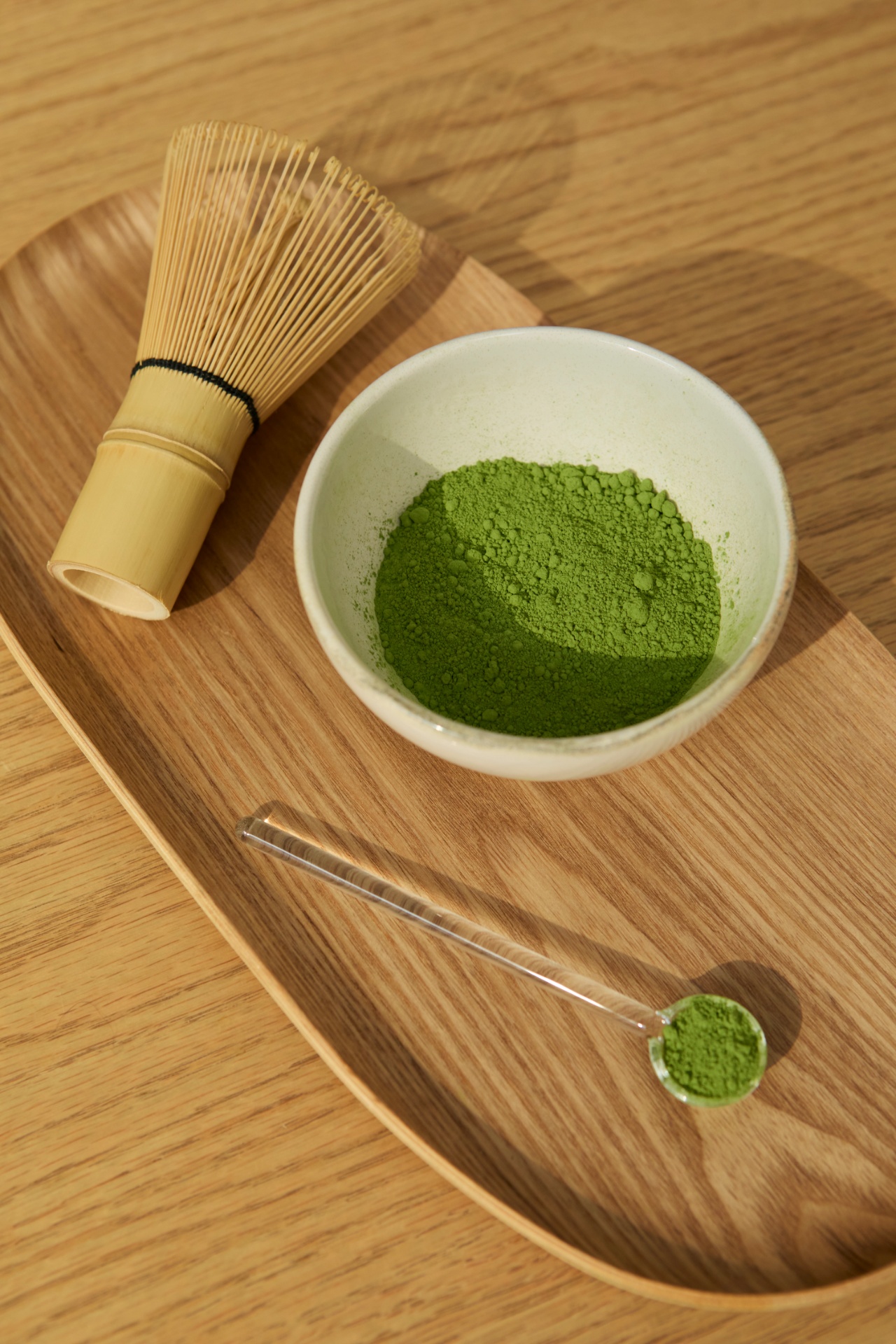 Bamboo whisk beside a bowl of loose matcha powder