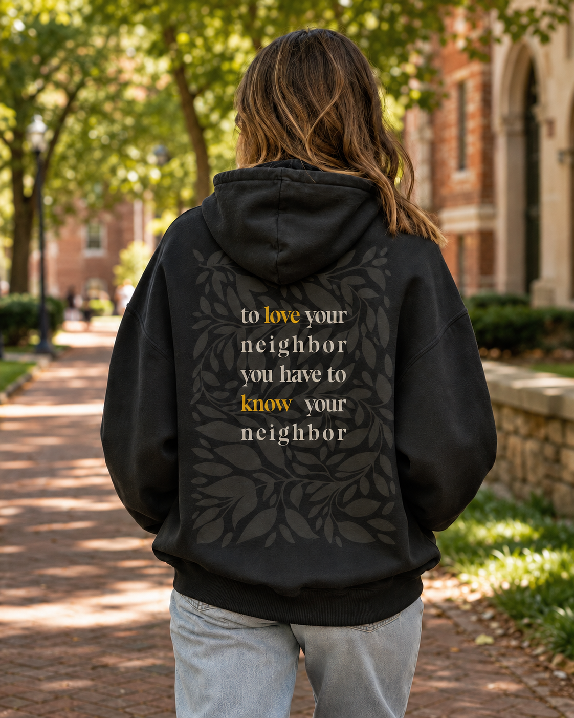 The back of a black hoodie reading to love your neighbor you have to know your neighbor