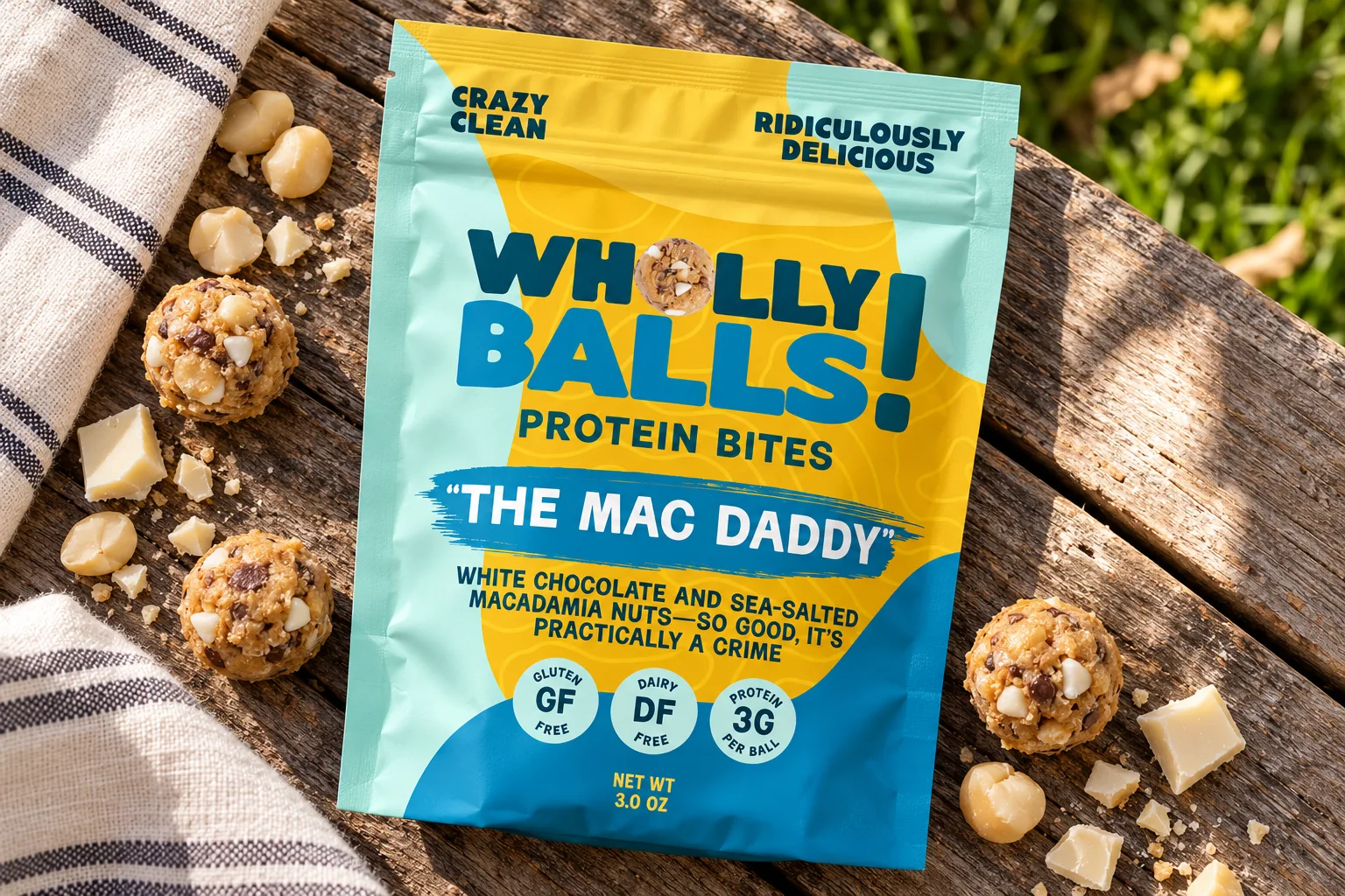 A Mac Daddy pouch on a weathered picnic table, scattered with macadamia nuts, white chocolate and protein bites