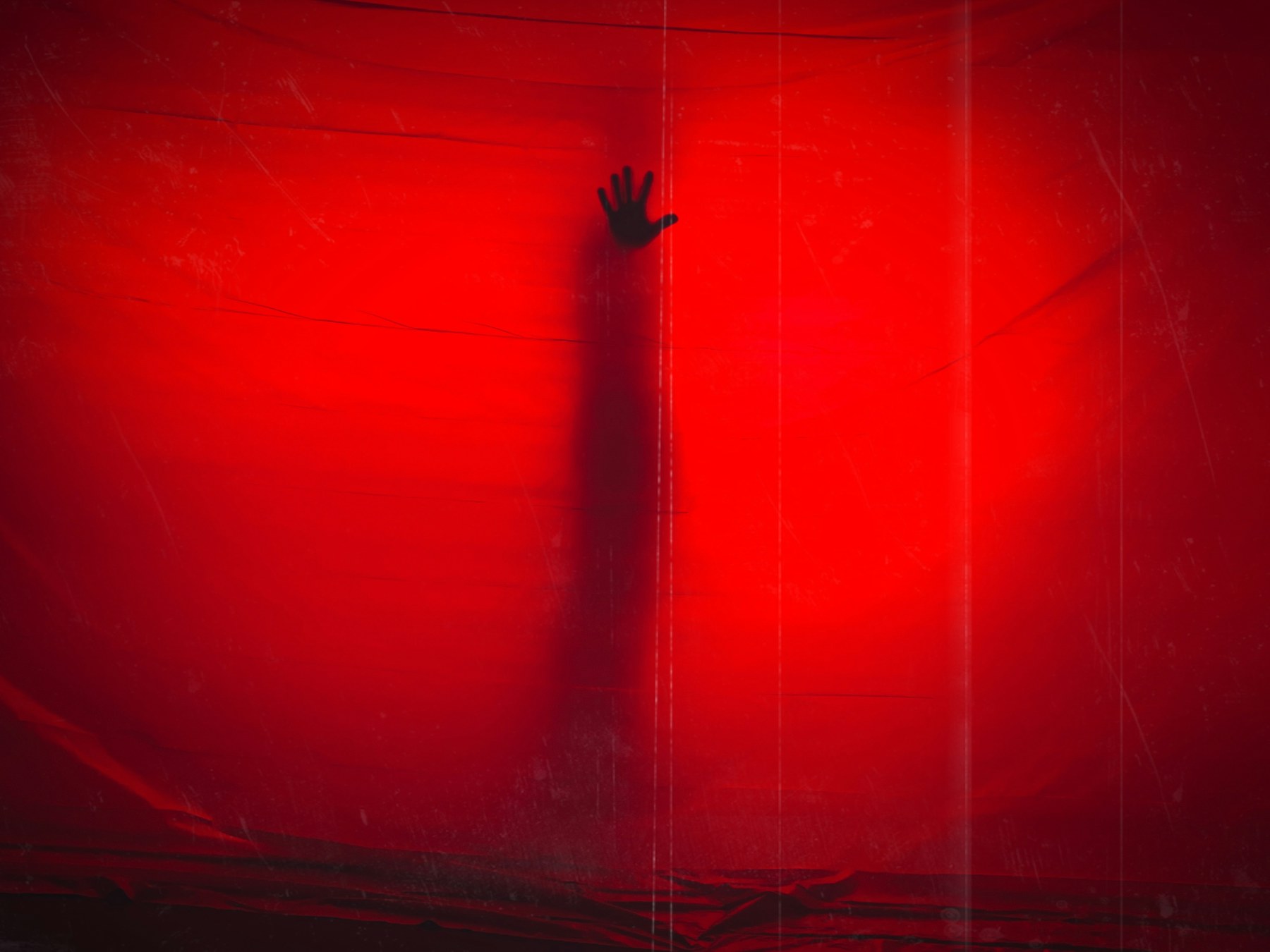 A hand reaching into a hazy red light, photographed with a film-like texture